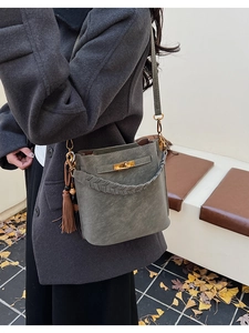Close-up of a retro grey-green bucket bag with metallic bar lock and woven handle