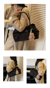 Detail of black wax leather tote bag with buckle and cute brown plush bear charm