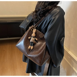 Detail of dark brown tote bag with retro wide patterned strap and rabbit charm accessory
