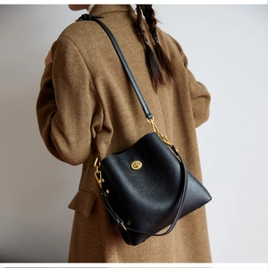 Detail of black pebbled leather bucket bag with gold twist lock and shoulder strap
