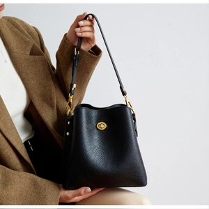 Detail of black pebbled leather bucket bag featuring a golden twist-lock clasp and strap