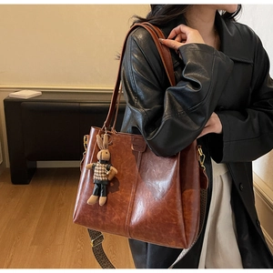 Detail of vintage brown tote bag with leather texture and wide printed crossbody strap