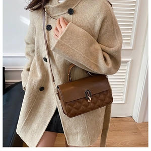 Deep brown quilted crossbody bag shown on beige coat in a cozy lifestyle setting