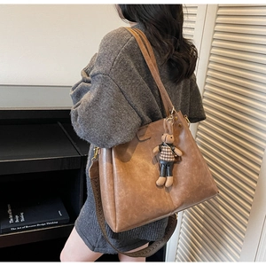 Detail of vintage brown tote bag featuring soft faux leather texture and plush bunny charm