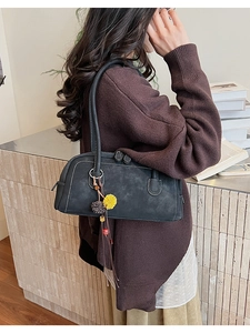 Detail of retro dark grey shoulder bag with white stitching and floral plush charm
