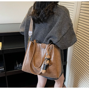 Detail of brown faux leather tote bag with colorful wide strap and rabbit charm accessory