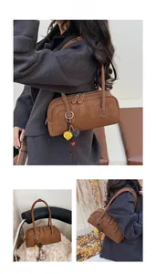 Detail of vintage brown shoulder bag featuring double zippers and decorative bag pendant