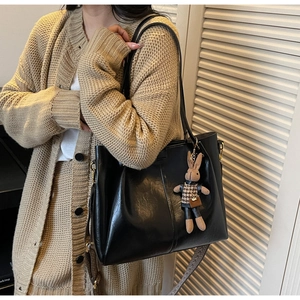 Detail of black tote bag with vintage wide strap and cute bunny pendant charm
