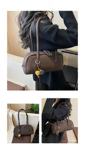 Detail of vintage brown shoulder bag with dual handles, zippers and plush ball pendant