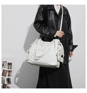 Detailed shot of white tote bag with side zippers and decorative drawstring details