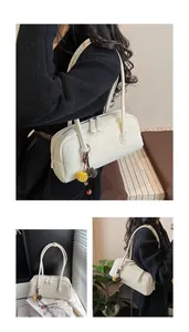 Detail of cream white Boston bag with litchi grain faux leather and floral charm