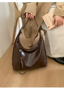 Close-up of soft brown retro hobo bag with polished leather texture and silver zipper detail