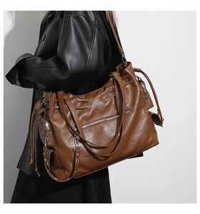 Detail of large caramel tote bag featuring textured leather, drawstring and side zippers