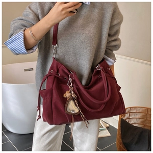 Detail view of burgundy tote bag with drawstring closure and chic mirror pendant charm