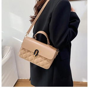 Close-up of beige quilted crossbody bag with gold-tone hardware on black blazer