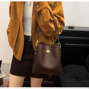 Close-up of a brown pebble leather bucket bag featuring a golden twist-lock buckle