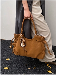 Detail of caramel faux leather tote with drawstring accents and leopard heart charm
