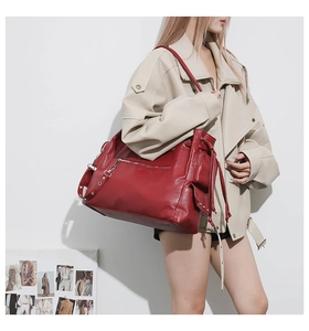 Detail of red oversized leather tote bag with functional pockets and silver metal hardware