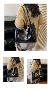 Detailed view of black leather tote bag with wide strap and cute rabbit charm on a model