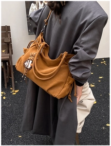 Detail of caramel suede tote bag with leopard charm and drawstring in outdoor setting