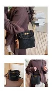 Detail of vintage matte black bucket bag with golden twist lock and tassel accent