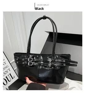Detail of black glossy patent leather shoulder bag with buckle straps and metal eyelets