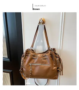 Detail of a brown textured faux leather tote bag featuring a silver zip pocket and drawstrings