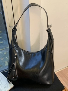 Minimalist black soft leather hobo bag with silver zippers and rivet details on seat