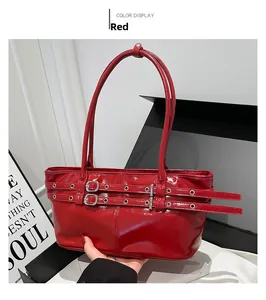 Close-up of red patent leather shoulder bag with decorative belts and metal eyelets