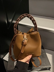 Brown bucket bag with woven handle and adjustable strap shown in a lifestyle setting