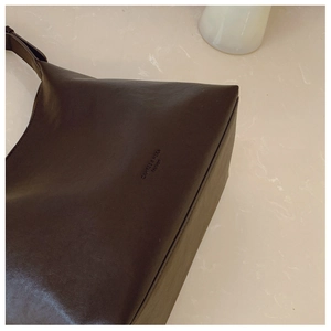 Detail view of coffee brown faux leather tote with minimalist side logo printing