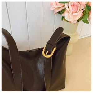 Close-up of deep brown soft leather tote bag with elegant gold buckle and matte texture