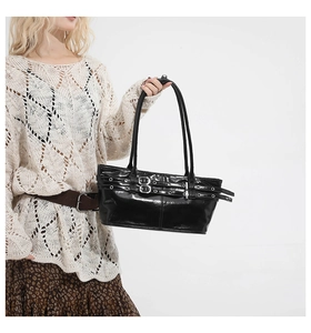 Detail of black glossy shoulder bag featuring silver buckles and double strap design