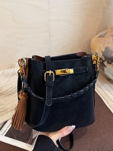 Retro black frosted bucket bag with gold lock and tassel charm on wooden background