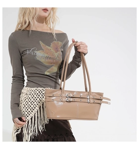 Detailed close-up of glossy patent leather shoulder bag with decorative silver belt buckles
