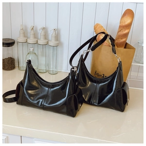 Détail des sacs portés épaule en cuir verni noir brillant avec poches latérales stylées