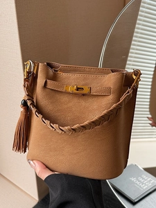 Retro camel matte bucket bag with golden twist lock and tassel charm shown in lifestyle setting