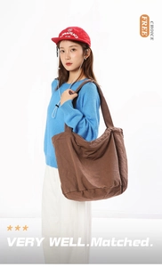 Detail of a dark brown washed canvas tote bag with thick texture and wide shoulder strap