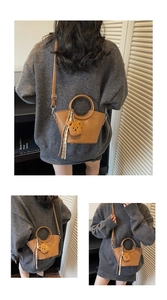 Detail view of a brown vintage bucket bag with round handles and bear charm accessory