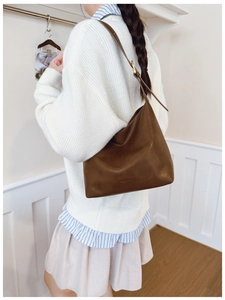 Detail of soft brown leather tote with adjustable strap and elegant gold embossed logo
