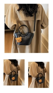 Detail of black semi-circular crossbody bag with round handle, plush bear and scarf deco