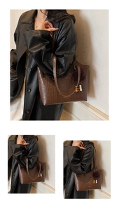 Detail of dark coffee croc-effect tote bag with plush ball and wooden bead charms
