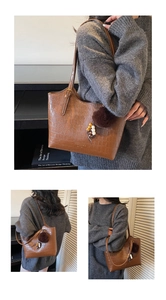 Close-up of brown crocodile pattern tote bag with plush ball and bead pendant