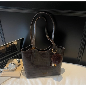 Detail of dark brown faux leather tote with crocodile pattern and plush ball charm