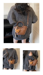 Detail view of brown shoulder bag with plush bear charm and silk scarf decoration