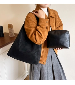 Detailed view of black matte oversized tote bag with a matching leather clutch bag