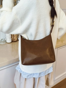 Minimalist deep brown matte leather tote bag worn as a crossbody with retro gold hardware