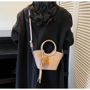 Detail of beige mini crossbody bag with round handle and cute bear charm pendant