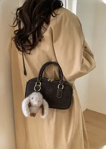 Detail of dark brown bowling bag with adjustable strap and plush rabbit charm