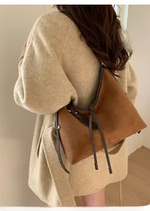 Détail du sac cabas en daim marron avec garniture en cuir et longues franges sur modèle